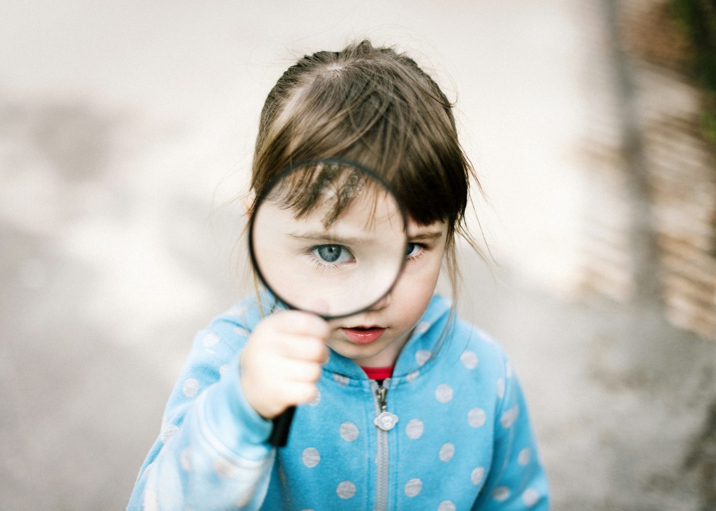 Child using a magnifying glass as a detective learning symbol