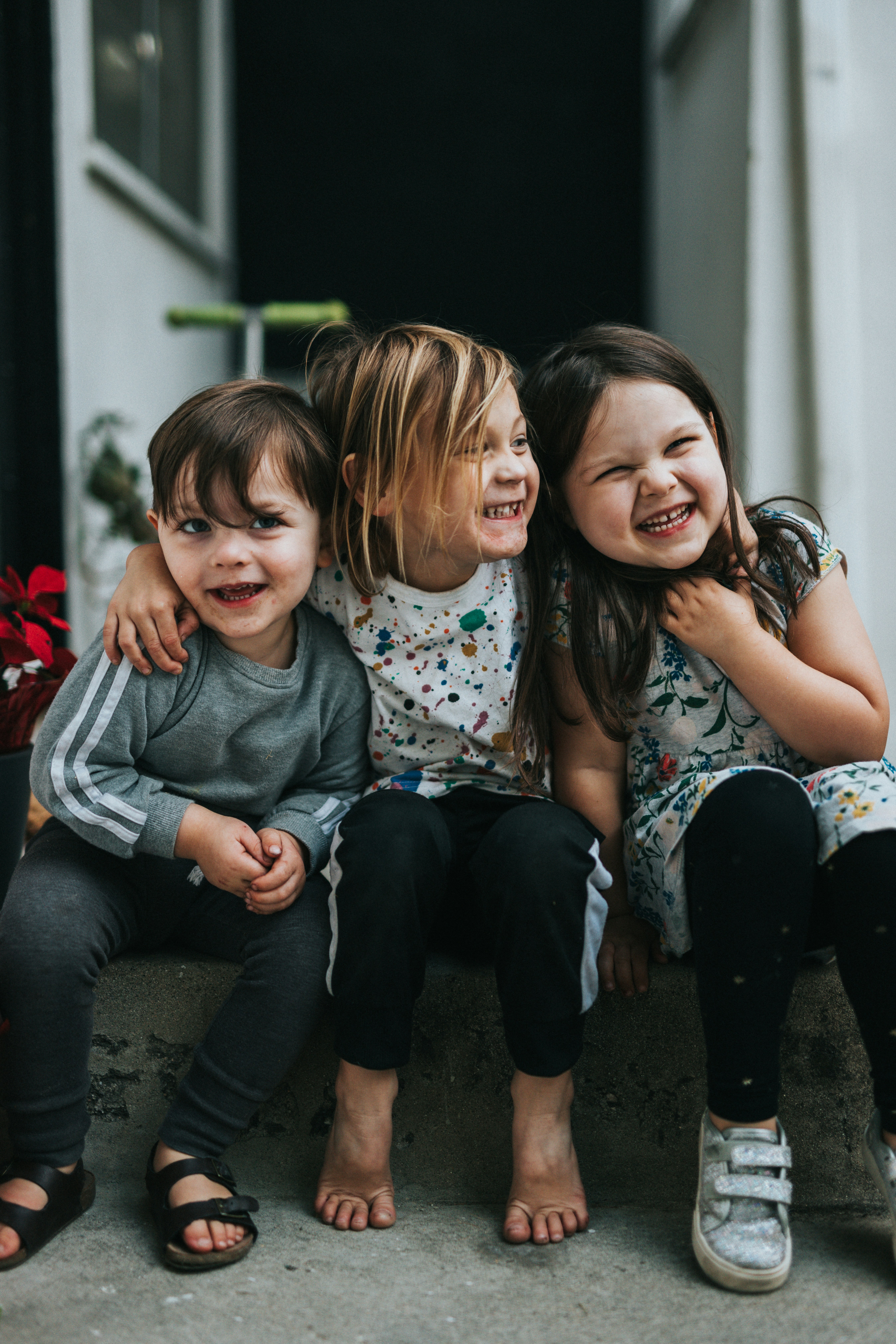 Three happy children sitting together on a doorstep